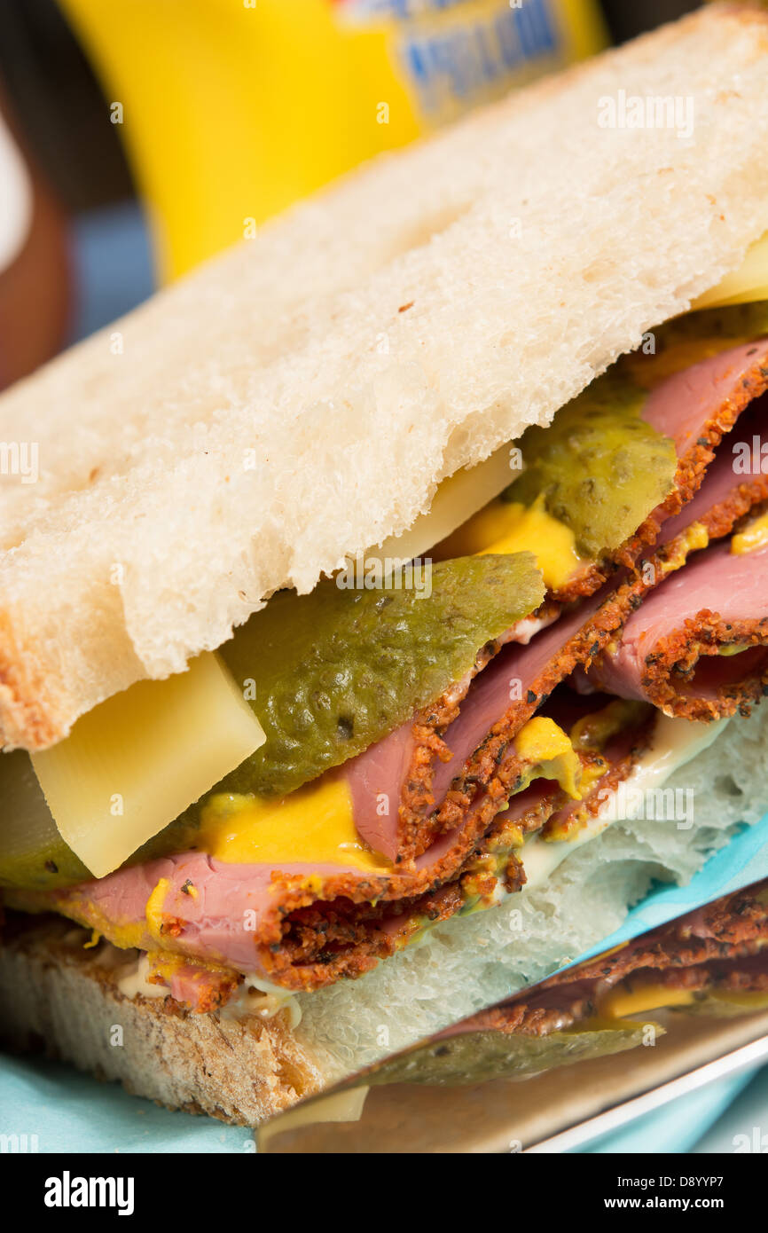 Un sandwich de style déli pastrami, de l'emmenthal, cornichons, moutarde et piment mayonnaise sur du pain au levain. Banque D'Images