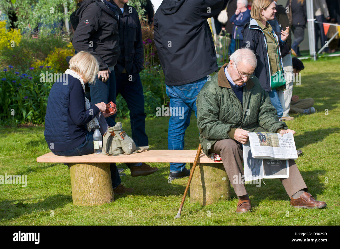 Man reading newspaper assis sur un banc à Hay Festival 2013 Hay-on-Wye Powys Pays de Galles UK Banque D'Images