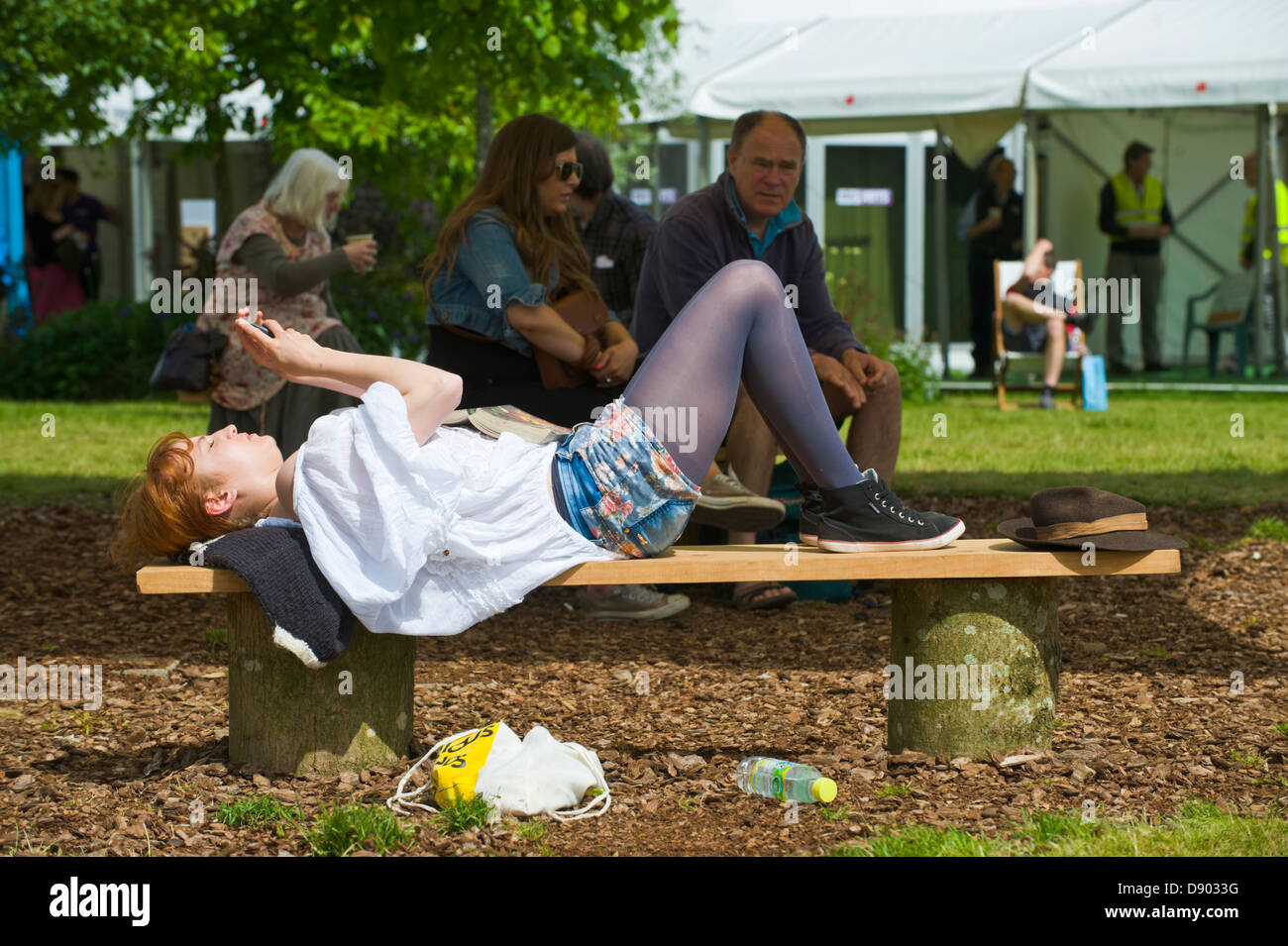 Young woman lying on bench in sunshine en utilisant smart phone at Hay Festival 2013 Hay-on-Wye Powys Pays de Galles UK Banque D'Images