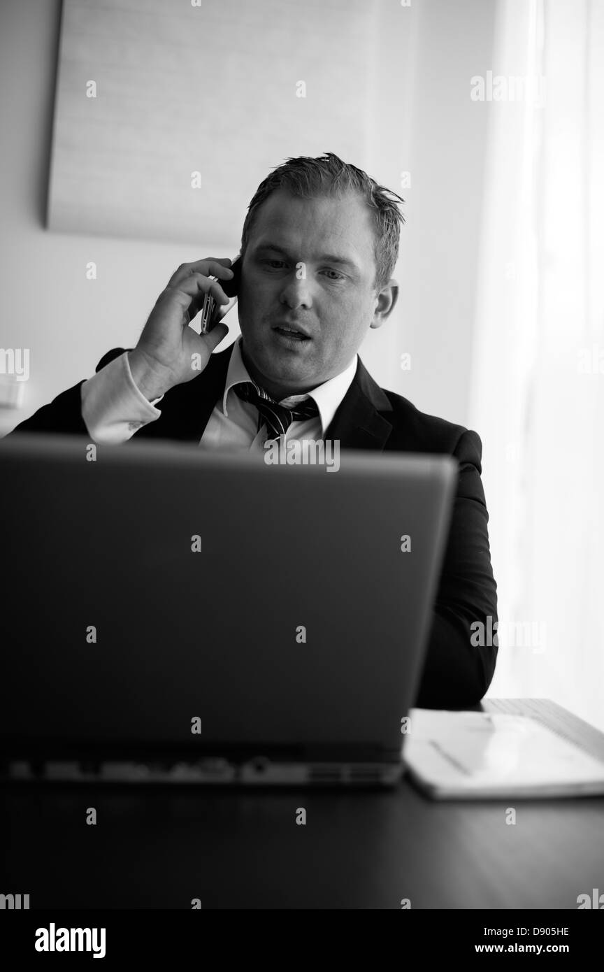 Businessman using laptop and talking on phone Banque D'Images
