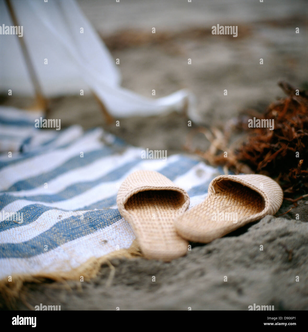 Une paire de chaussons et une couverture sur une plage de sable. Banque D'Images