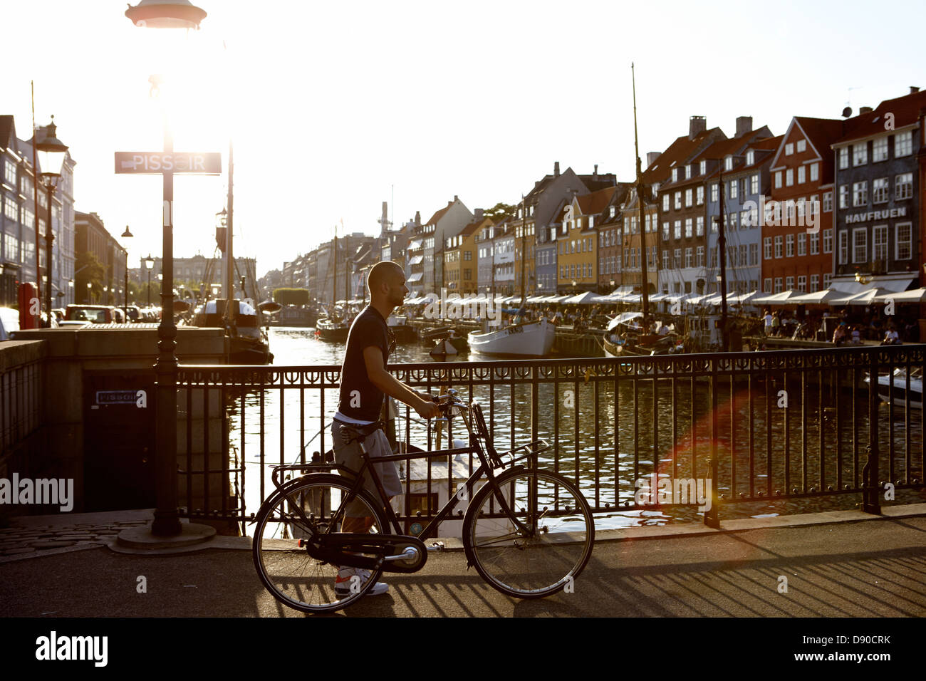 Homme marchant avec un vélo contre la lumière, le Danemark. Banque D'Images