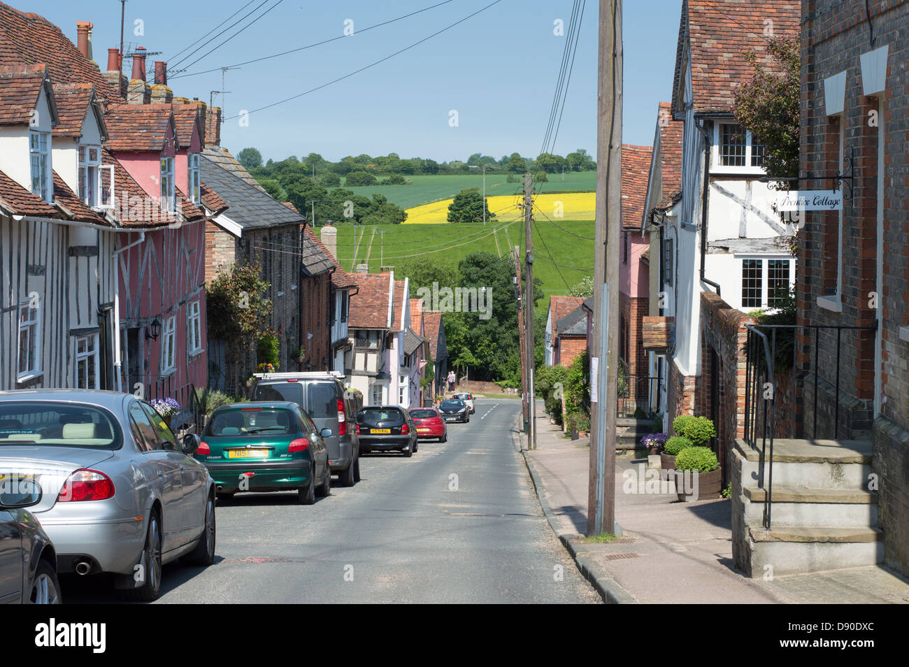 Maisons et voitures stationnées dans la rue Prentice, Lavenham, Suffolk, Angleterre, avec des champs au-delà. Banque D'Images