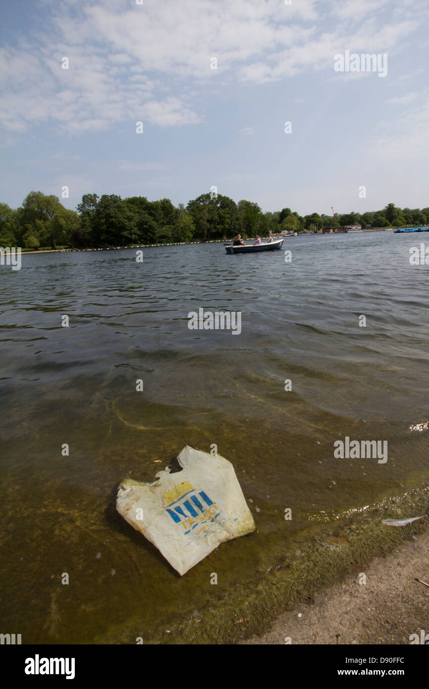 Un sac en plastique Tesco mis au rebut flotte dans les eaux de la Serpentine, Hyde Park, Londres, mettant en évidence les problèmes persistants liés aux déchets et à la pollution urbaine dans les espaces verts publics Banque D'Images