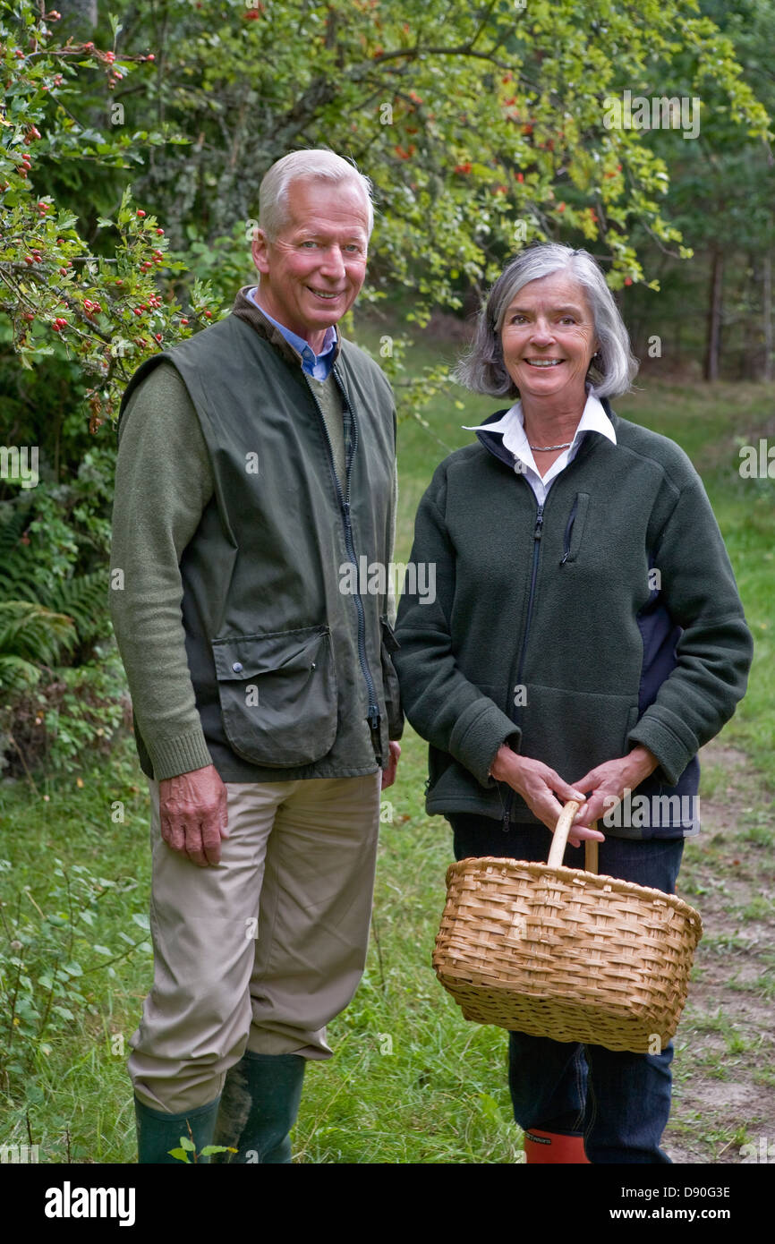 Senior couple holding basket debout sur sentier, smiling Banque D'Images