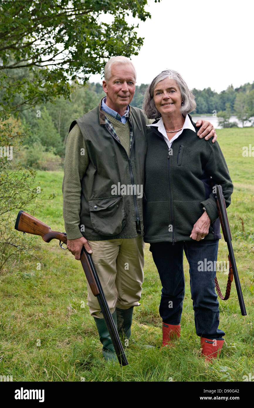 Senior couple holding rifle, smiling Banque D'Images