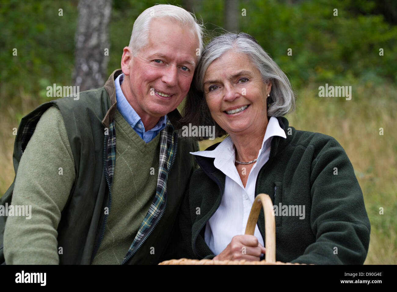 Senior couple holding basket, smiling Banque D'Images