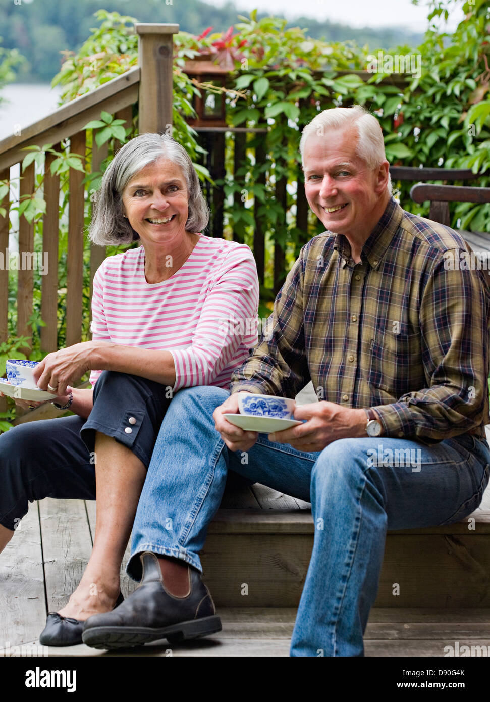 Senior couple sitting on steps, le café, smiling, portrait Banque D'Images