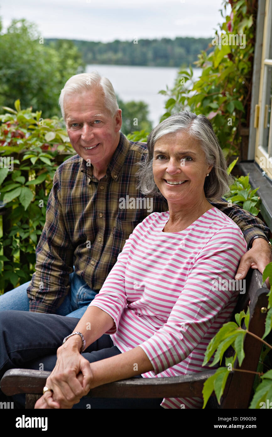 Senior couple sitting on bench, smiling Banque D'Images