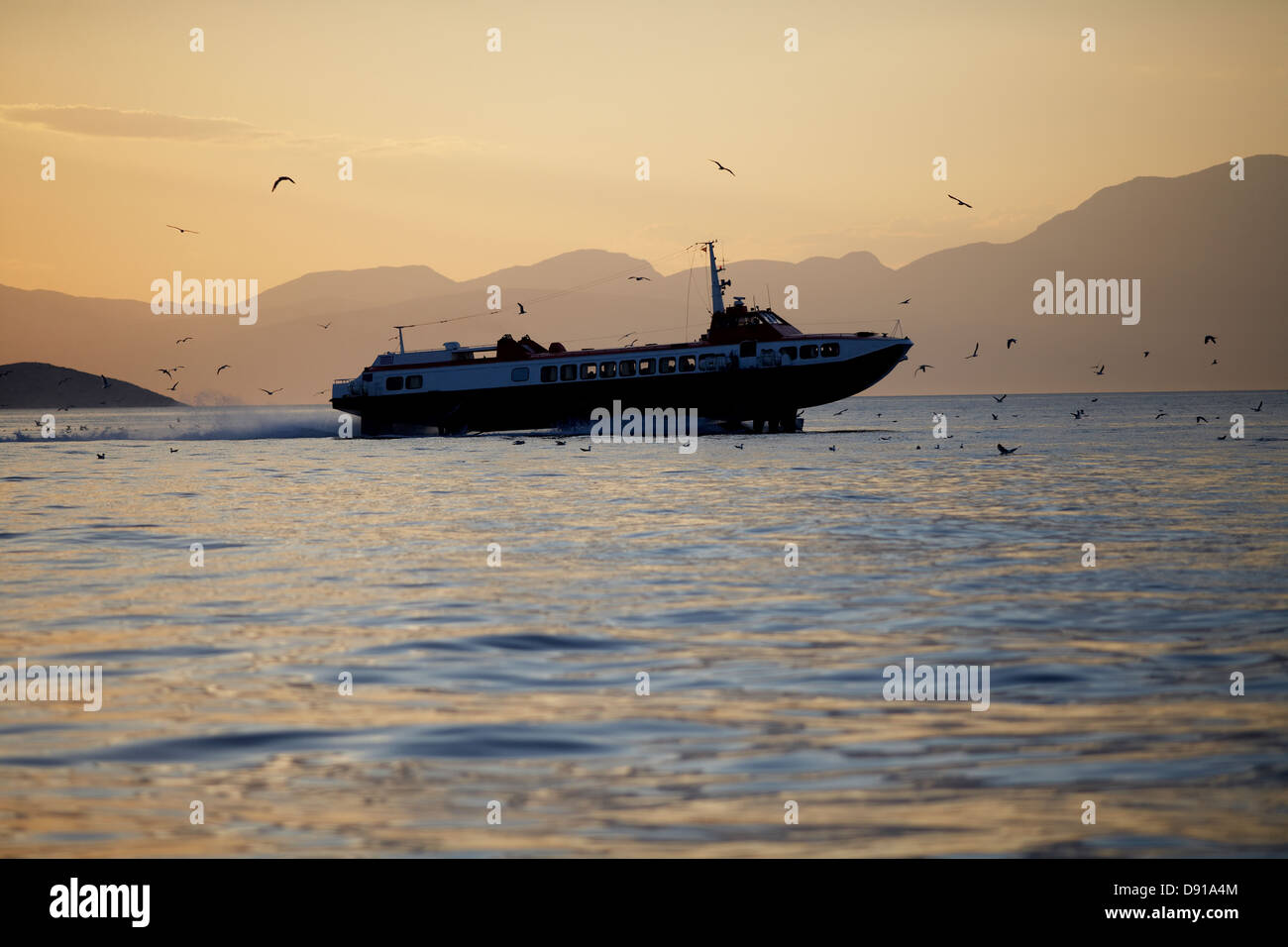 Un bateau et des oiseaux dans le coucher du soleil, la Grèce. Banque D'Images