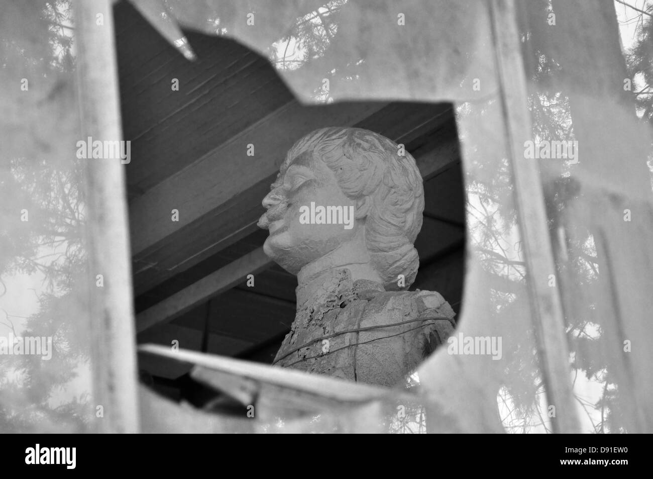 Statue de Rigas Feraios révolutionnaire grecque à travers les vitres brisées de la maison abandonnée de l'artiste Nikolaos Pavlopoulos. Banque D'Images