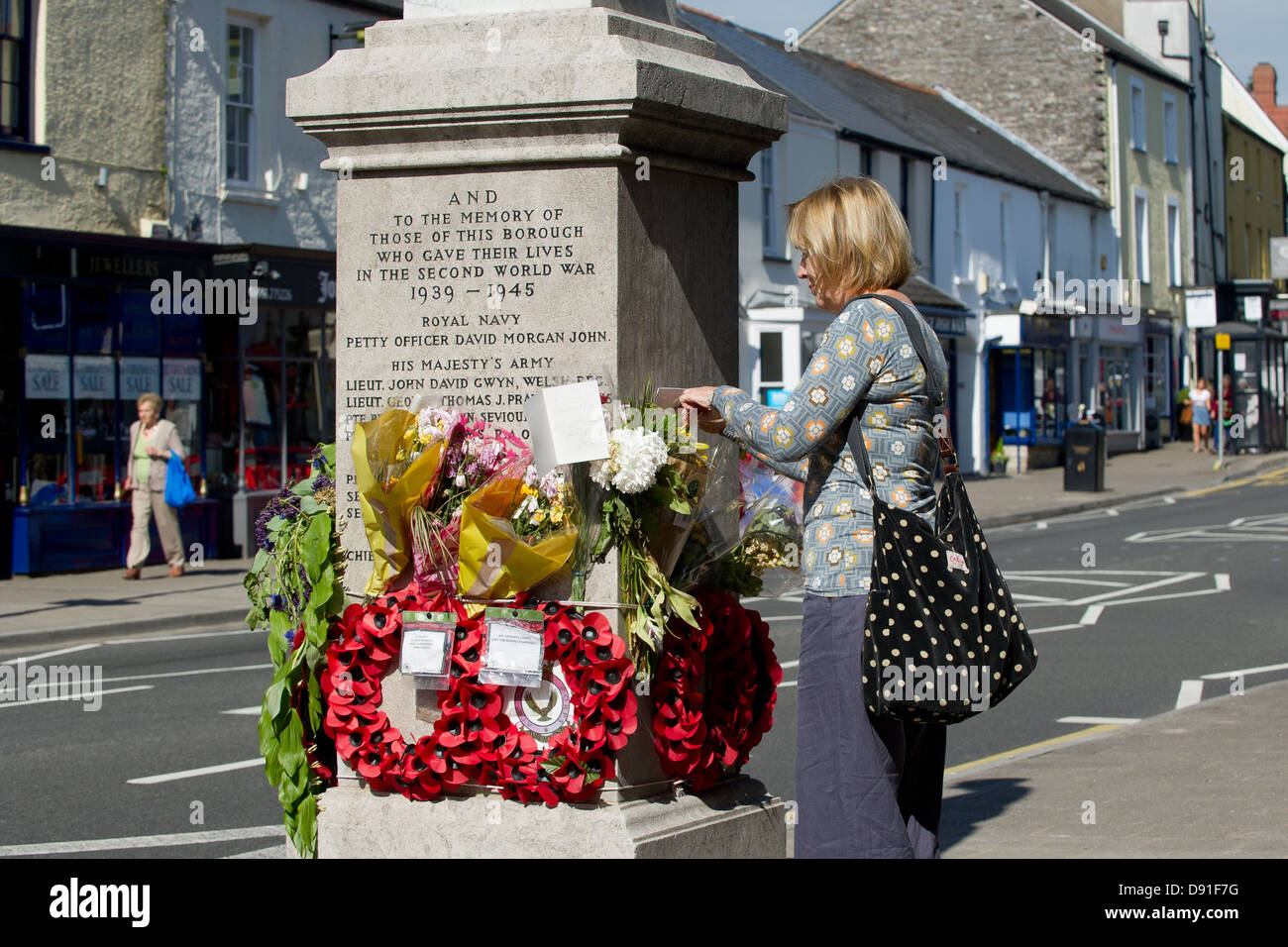 Une femme s'arrête de lire les messages laissés avec des bouquets sur le monument aux morts de Bridgend, au Royaume-Uni. Banque D'Images