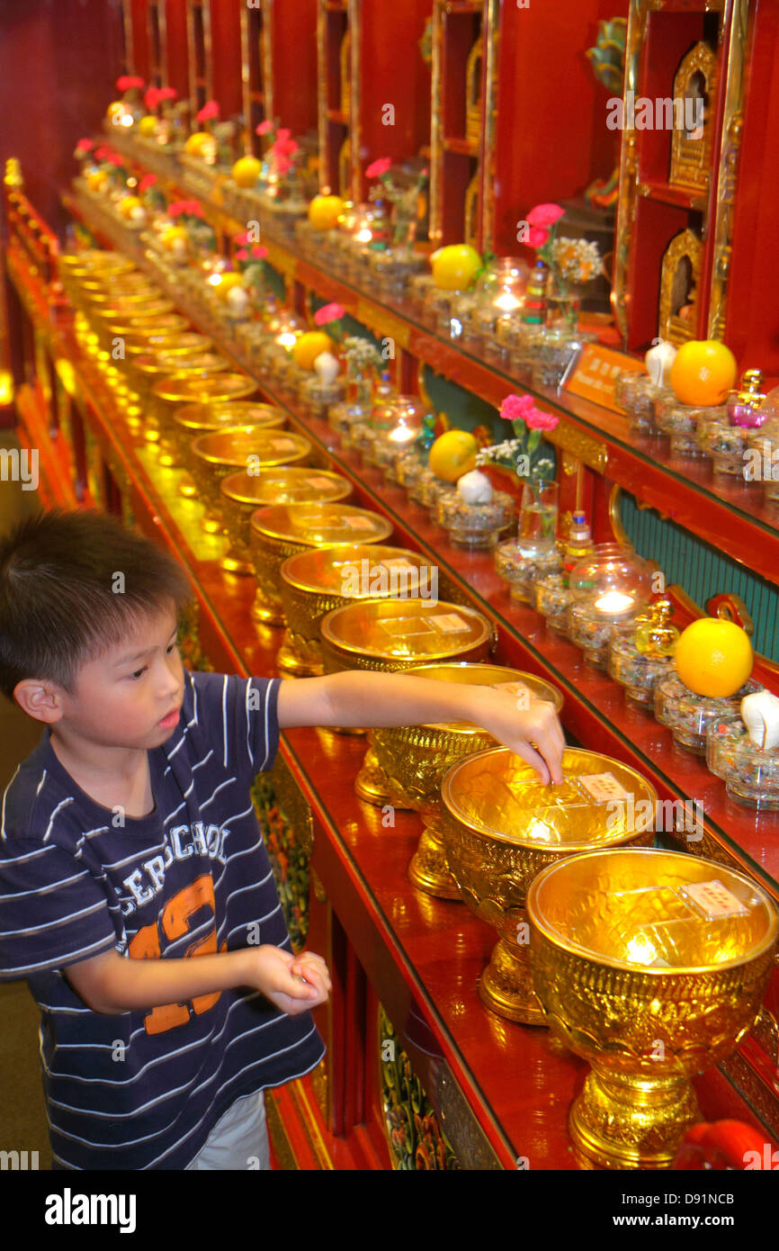 Chinatown de Singapour, Temple et musée de la relique de Bouddha Tooth, sanctuaire, religieux, asiatique garçon garçons hommes enfants enfants enfants faire don, pièces de monnaie, mettre dans, bateaux, urnes, gol Banque D'Images