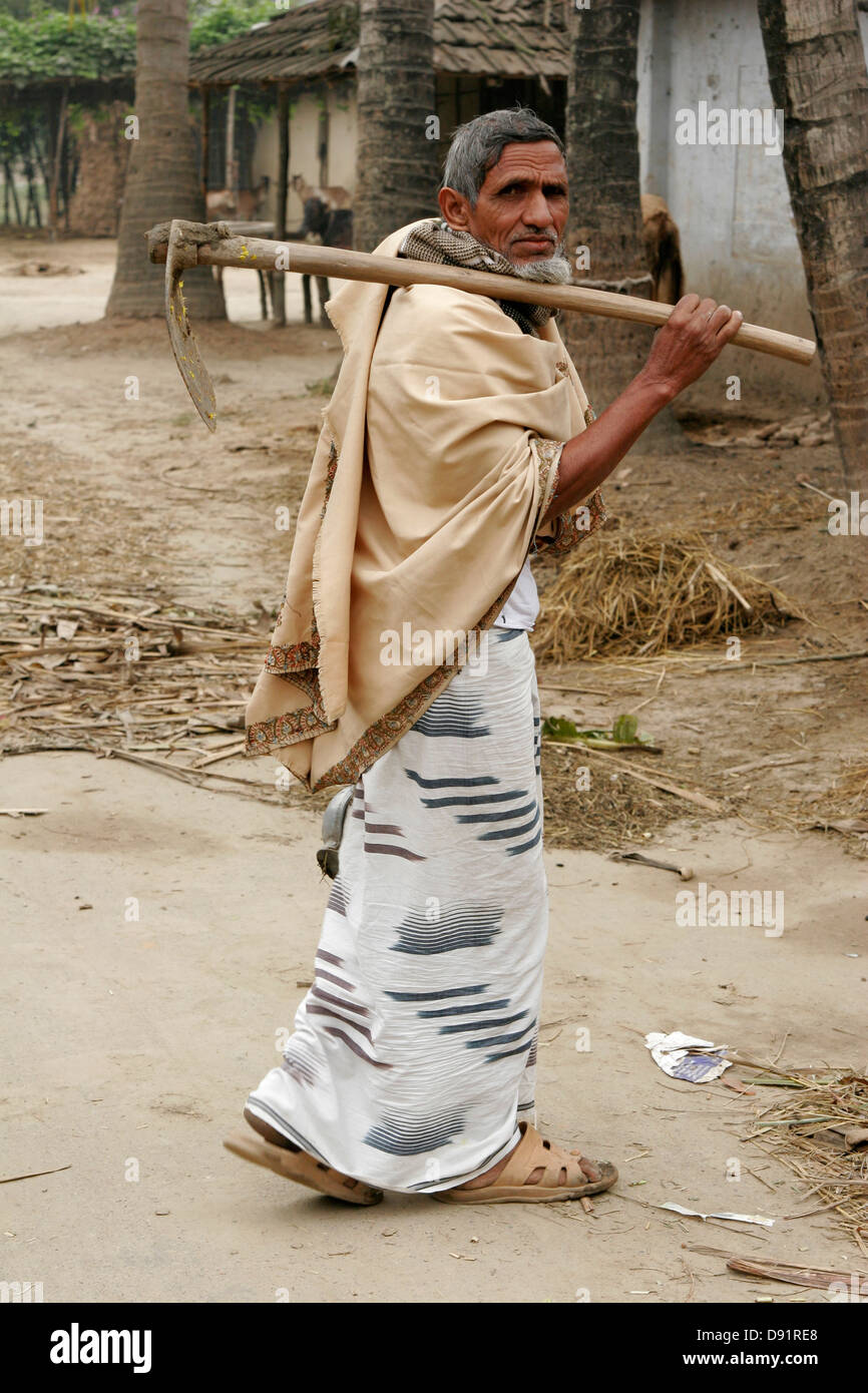 Homme marchant avec une faux sur la route en milieu rural au Bangladesh Banque D'Images