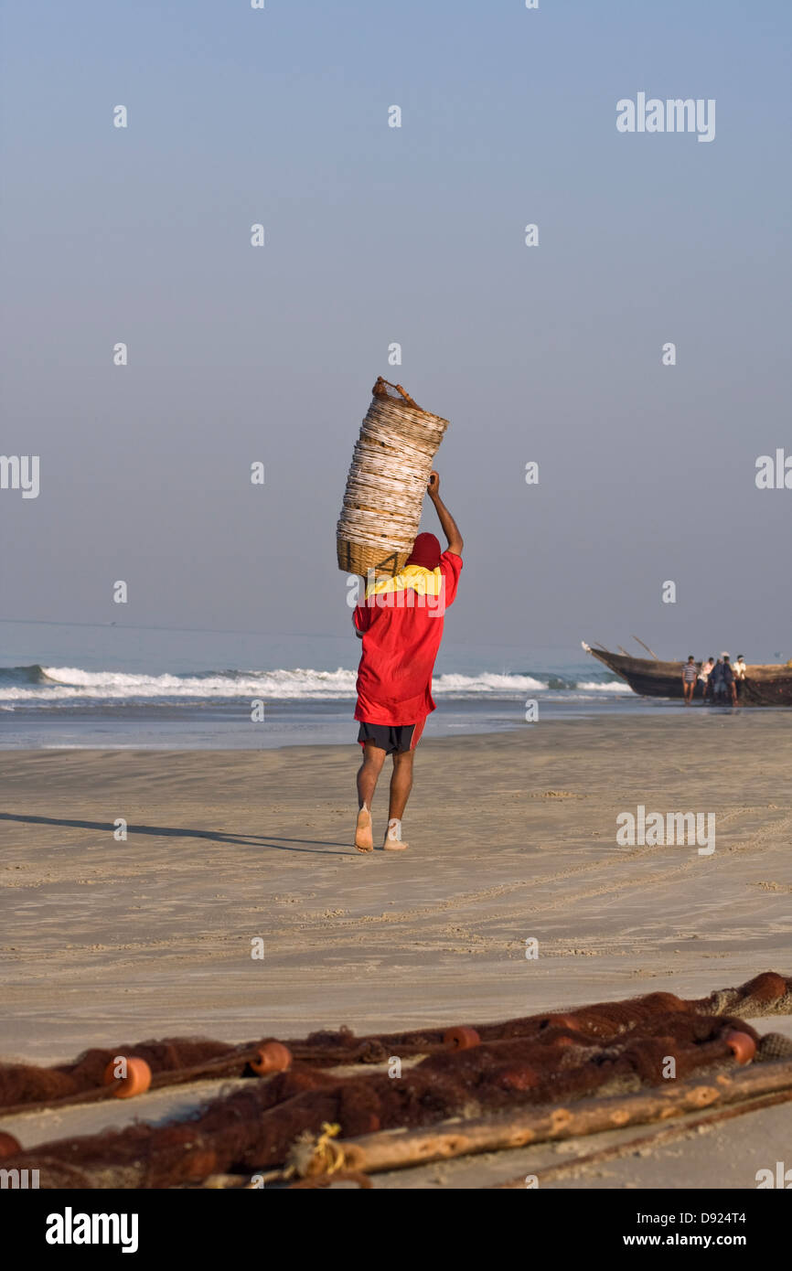 L'Asie, l'Inde, Goa, Benaulim, un pêcheur porte des paniers de poisson vide sur son épaule Banque D'Images