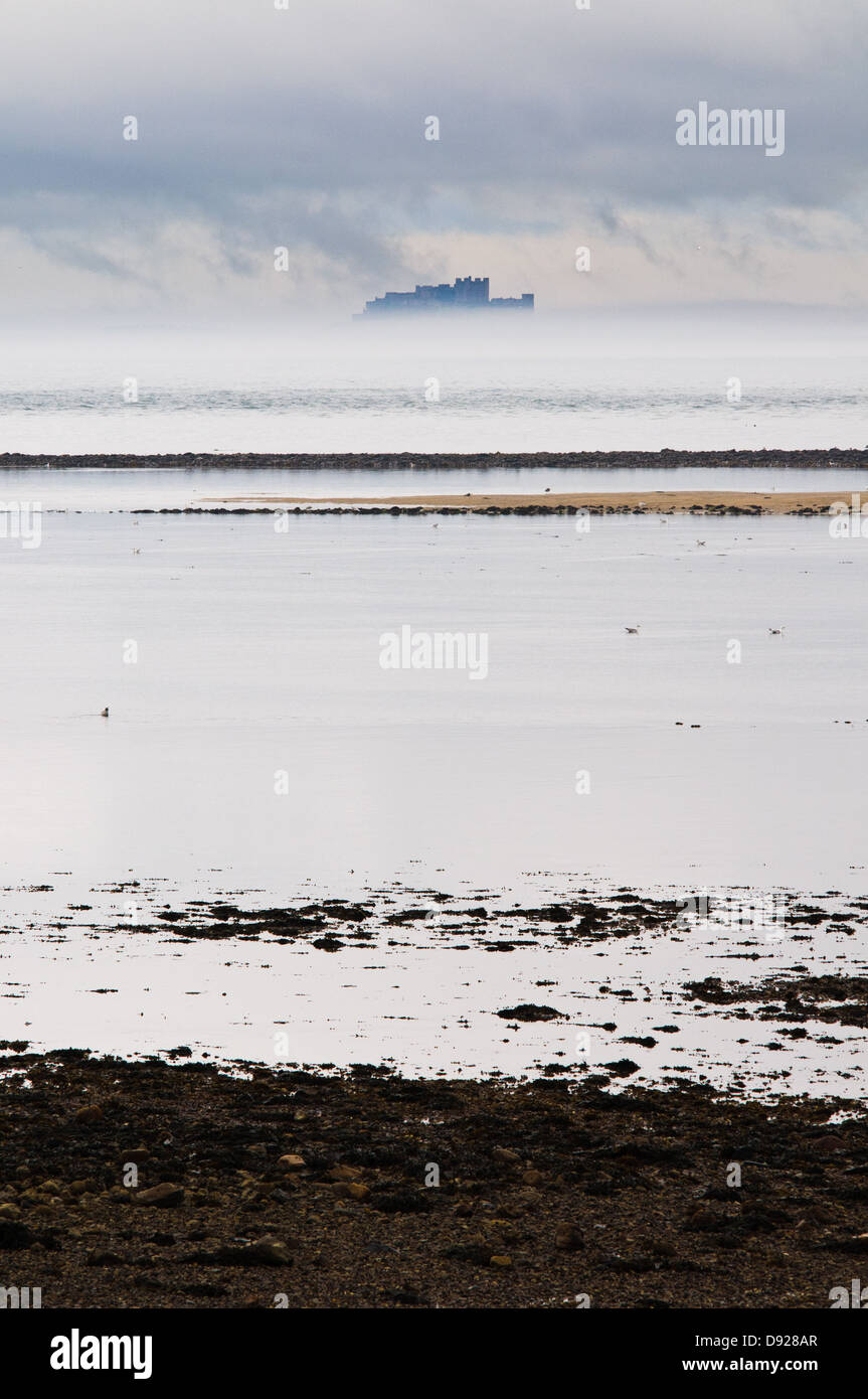 Château de Bamburgh comme vu par une bande de bruine de Lindisfarne Harbour Banque D'Images