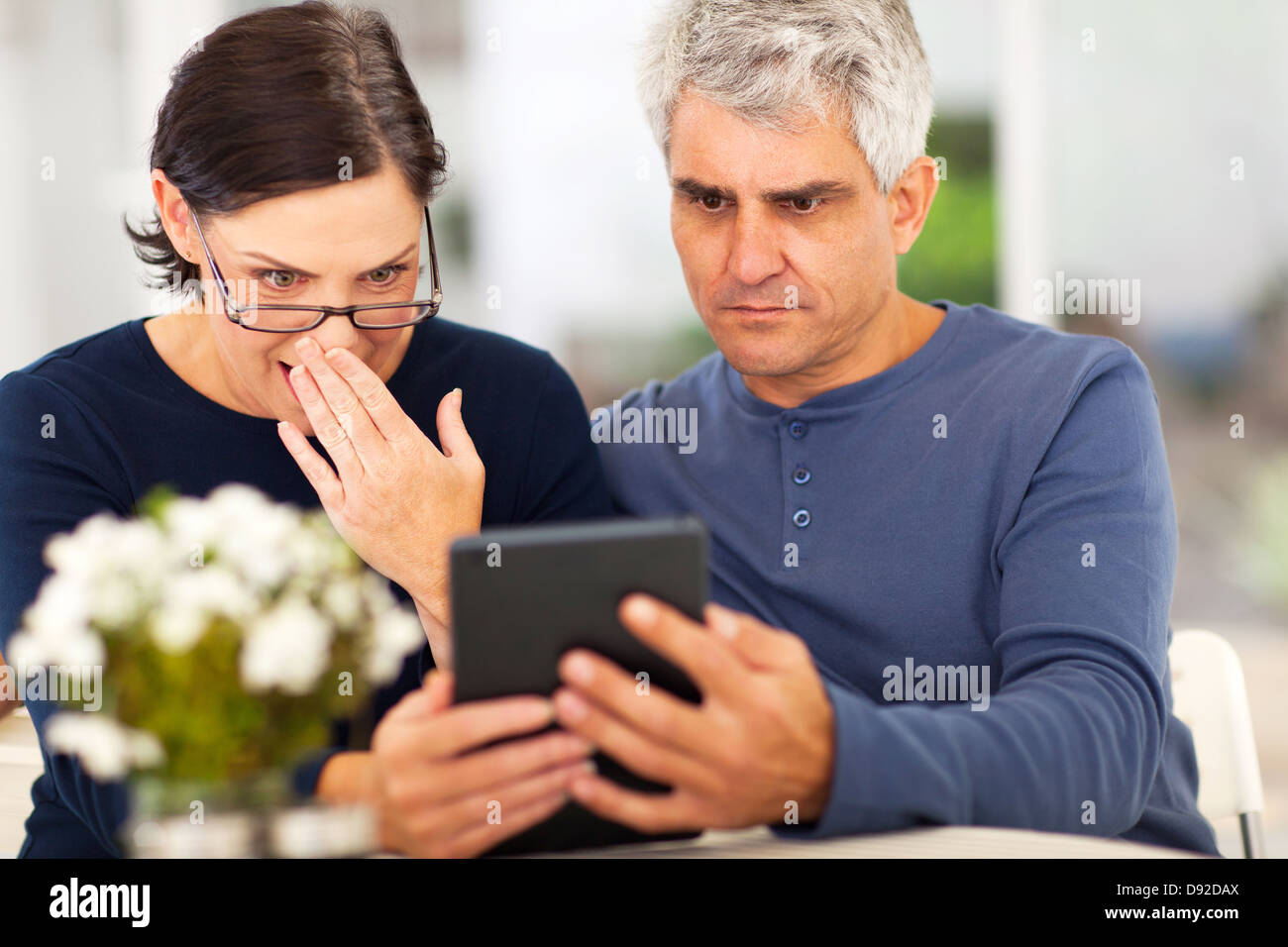 Couple d'âge moyen lecture nouvelle choquante sur tablet computer Banque D'Images
