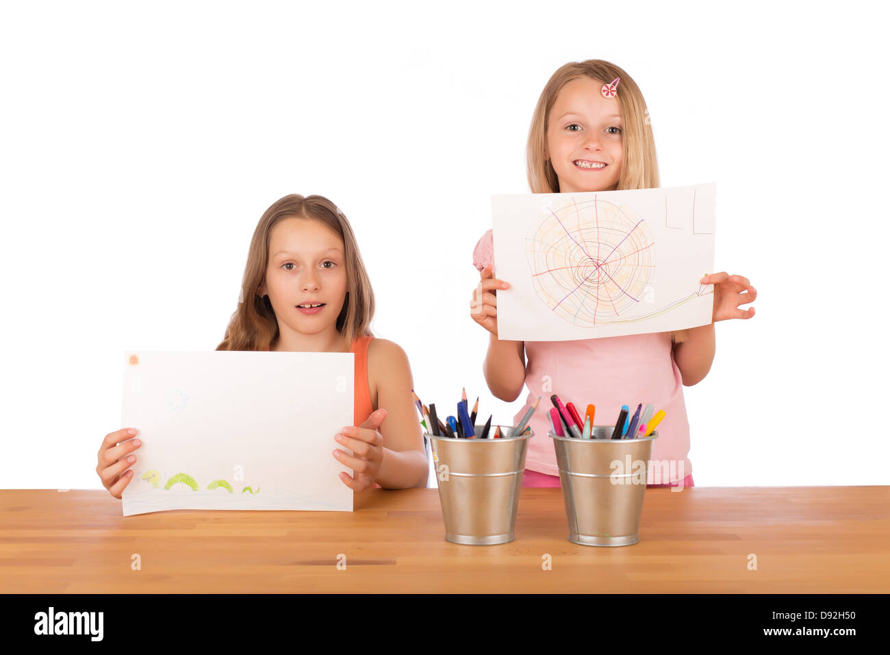 Deux sœurs aux cheveux blonds en souriant et montrant leur super dessins à une table en bois avec porte-crayons métalliques. Banque D'Images