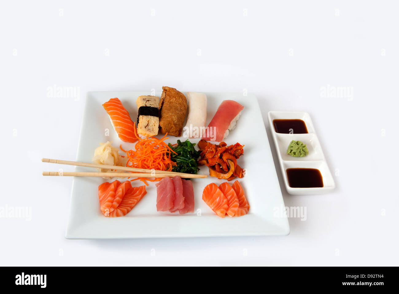 Assortiment de sushi et sashimi sur une plaque carrée blanche avec des baguettes Banque D'Images