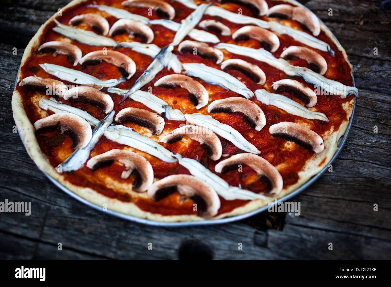 Un champignon, d'anchois et de la sauce tomate pizza avant la cuisson Banque D'Images