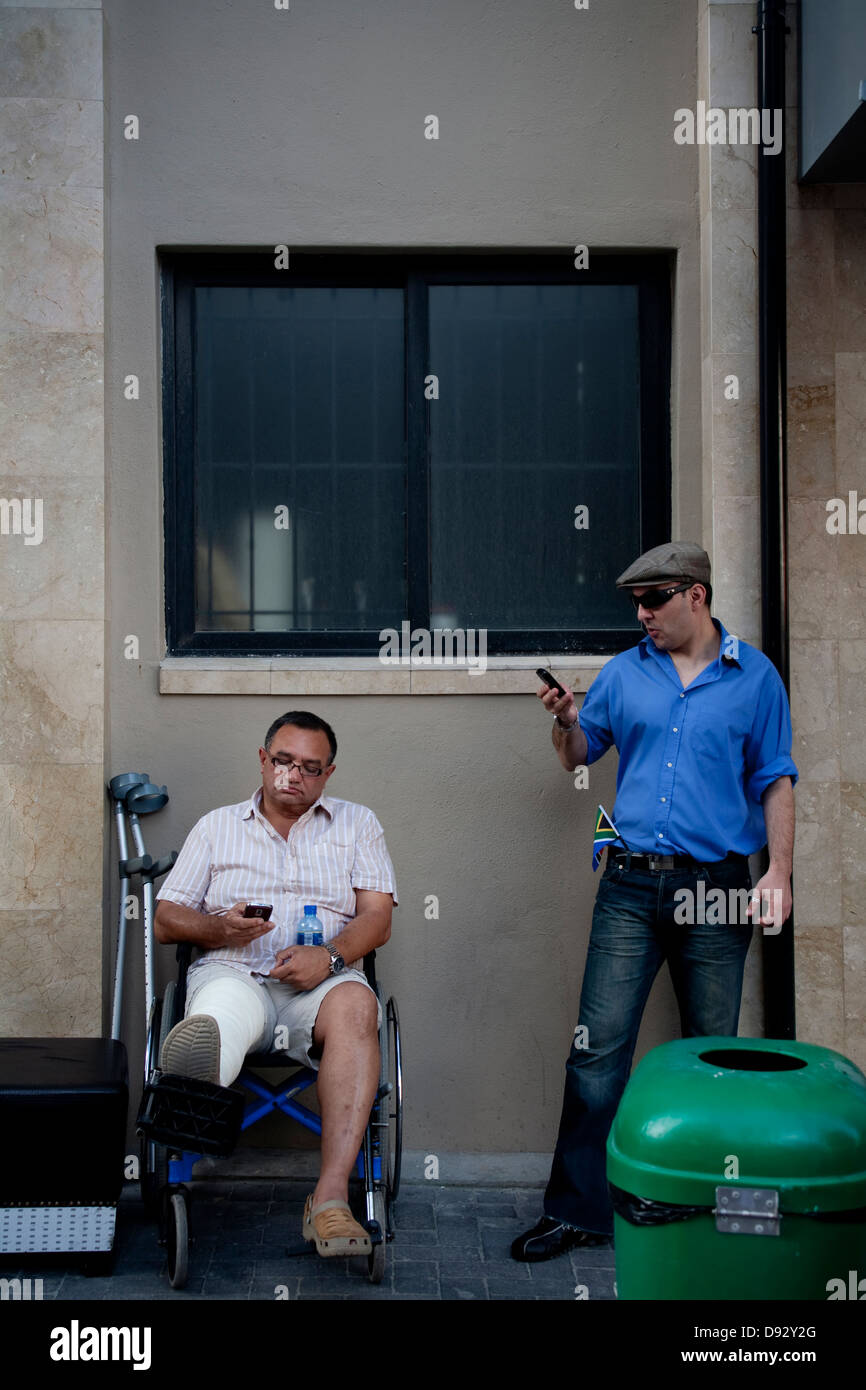Deux fans de football regardez les téléphones cellulaires pendant la coupe du monde FIFA tirage final carnival sur la rue Longue à Cape Town Afrique du Sud l'un est Banque D'Images Deux fans de football regardez les téléphones cellulaires pendant la coupe du monde FIFA tirage final carnival sur la rue Longue à Cape Town Afrique du Sud l'un est Banque D'Images