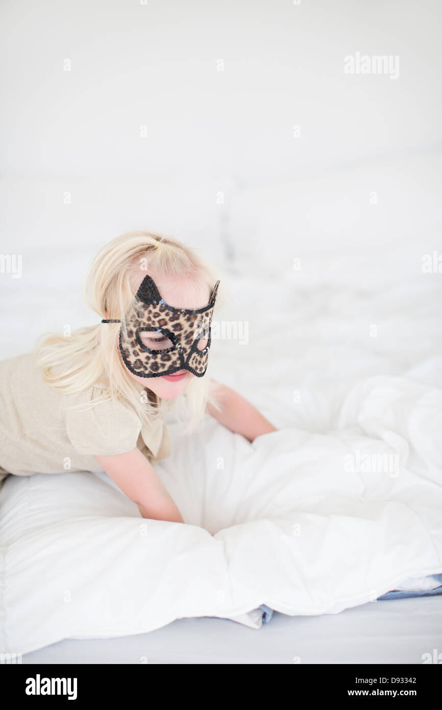 Cat Girl wearing mask ramper sur le lit Banque D'Images