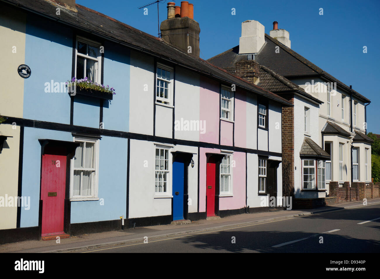 Woodfield couleur cottages - une rangée de maisons mitoyennes contre un ciel bleu clair, en Ashtead, Surrey, Angleterre, Royaume-Uni. Banque D'Images