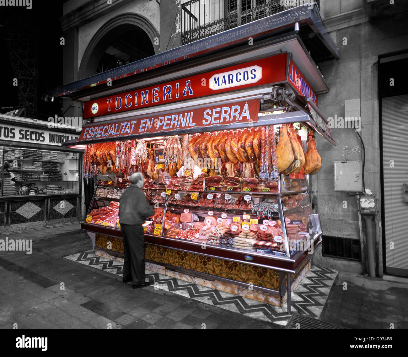 Un homme l'achat d'un vendeur de viande à un marché couvert dans le centre de Barcelone, Espagne, Europe. Les prix affichés sont en pesetas pre-euro. Couleur sélective. Banque D'Images