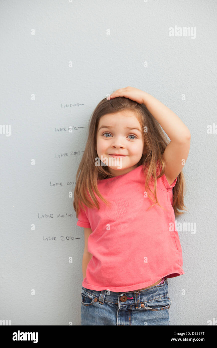 Caucasian girl measuring her hauteur sur mur Banque D'Images