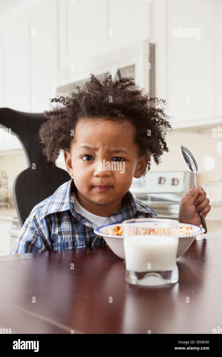 Mixed Race boy eating at table Banque D'Images