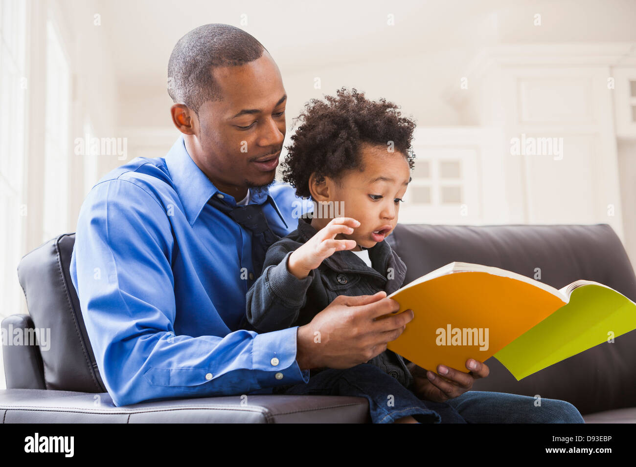 Père et fils lecture sur canapé Banque D'Images