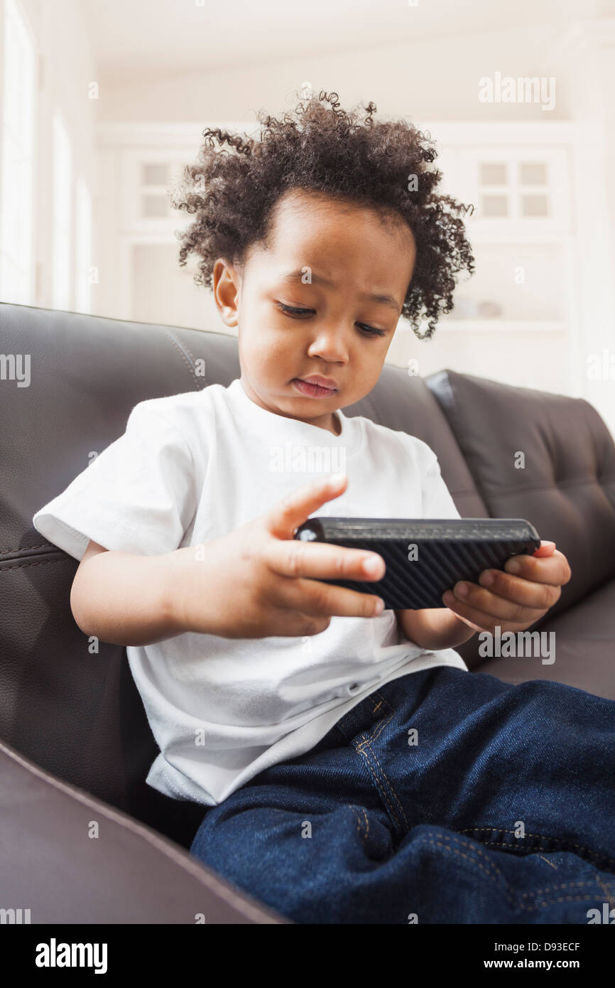 Mixed Race boy playing with cell phone on sofa Banque D'Images