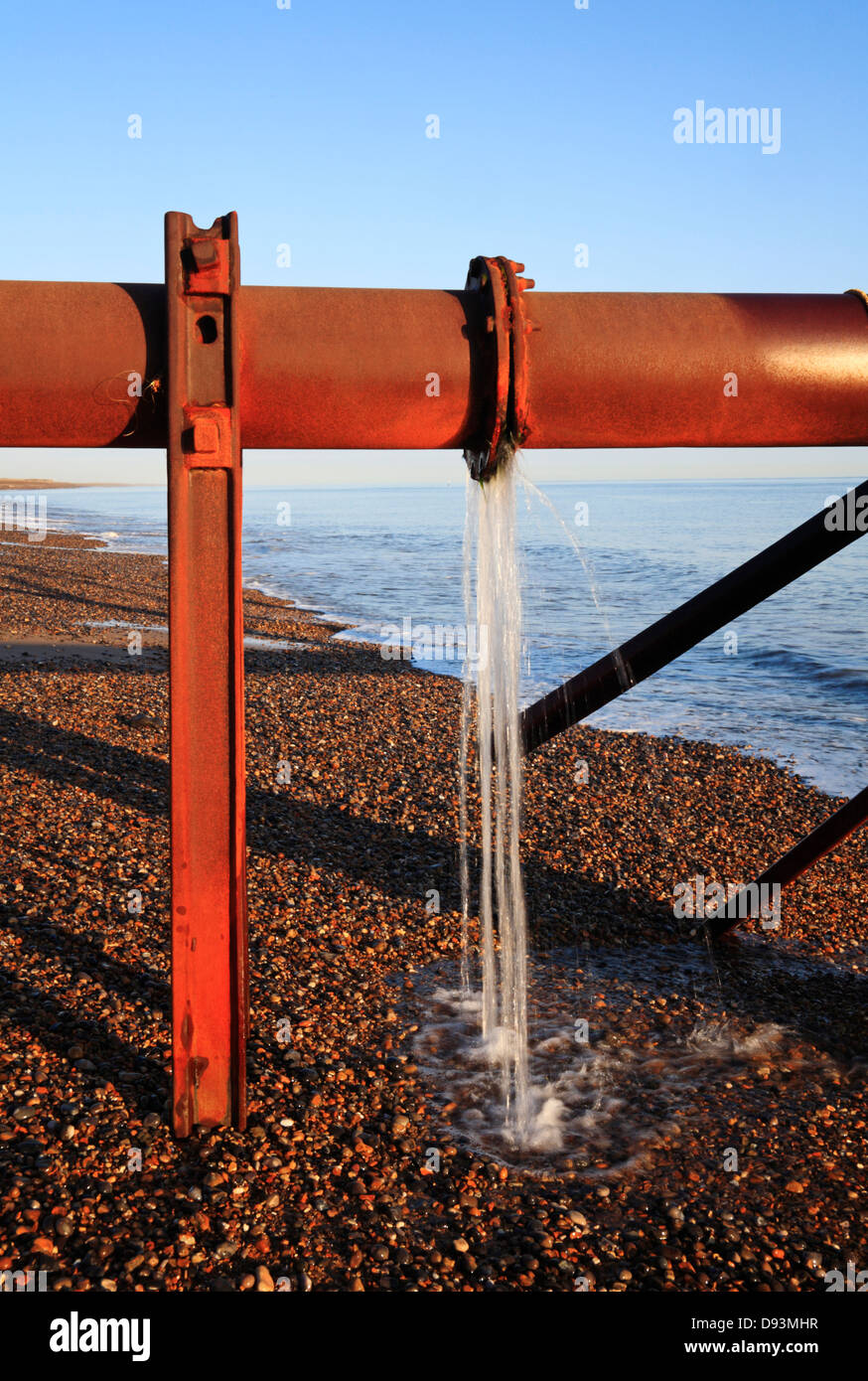 Vue d'une fuite sur une bride de tuyau d'exutoire transportant de l'eau de source de mer à Weybourne, Norfolk, Angleterre, Royaume-Uni. Banque D'Images