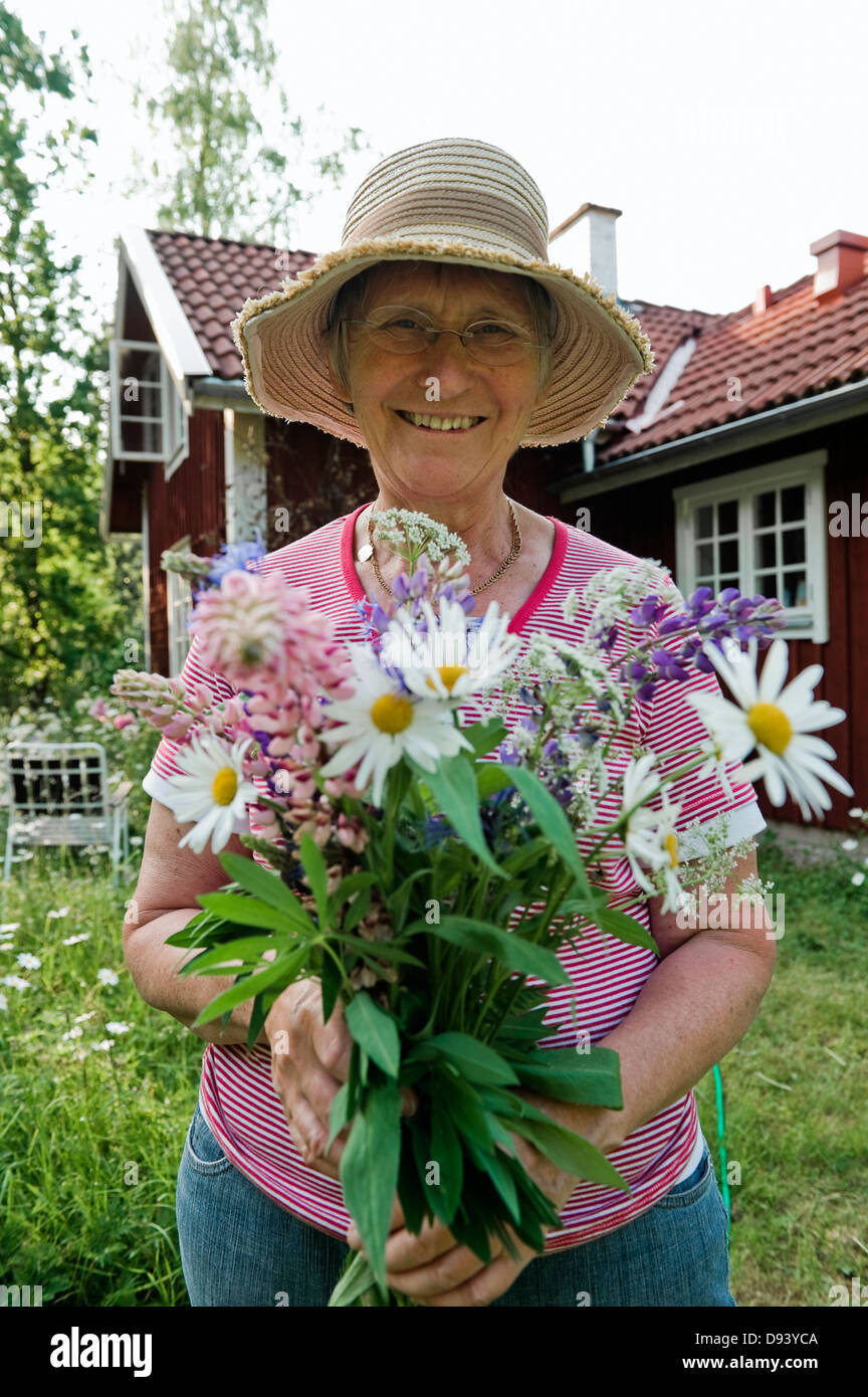 Senior woman holding Flowers en face du chalet Banque D'Images