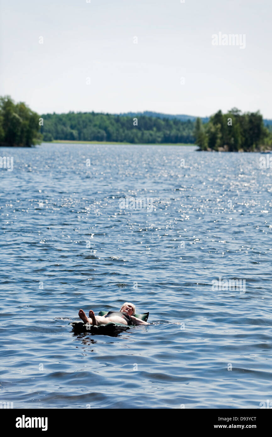 Femme couchée sur le lit et l'air flottant sur le lac de Banque D'Images