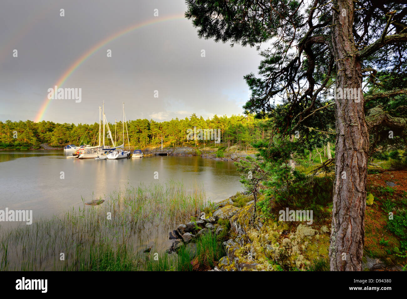 Arc-en-ciel sur petite baie avec des bateaux amarrés dans la voile Banque D'Images
