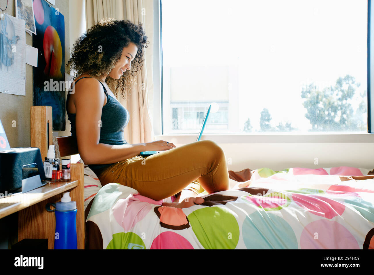 Mixed Race college student using laptop in dorm Banque D'Images