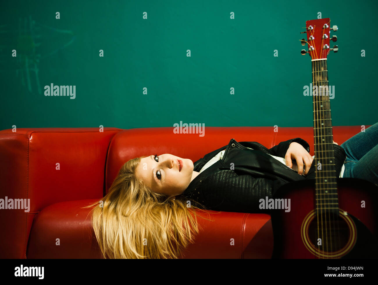 Woman Lying on Sofa avec guitare acoustique Banque D'Images