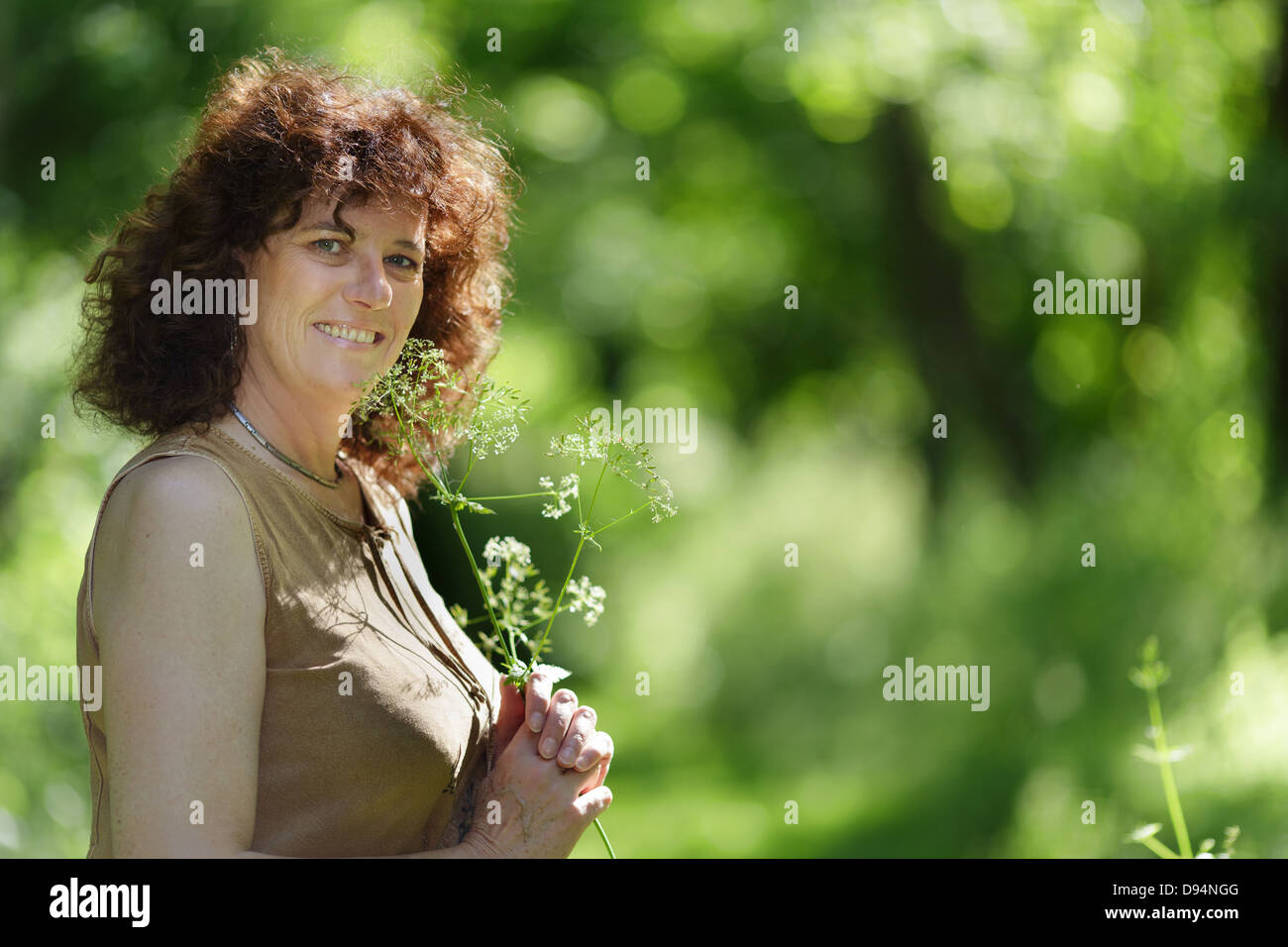 Middle aged woman holding profiter de la nature en forêt de fleurs sauvages Banque D'Images