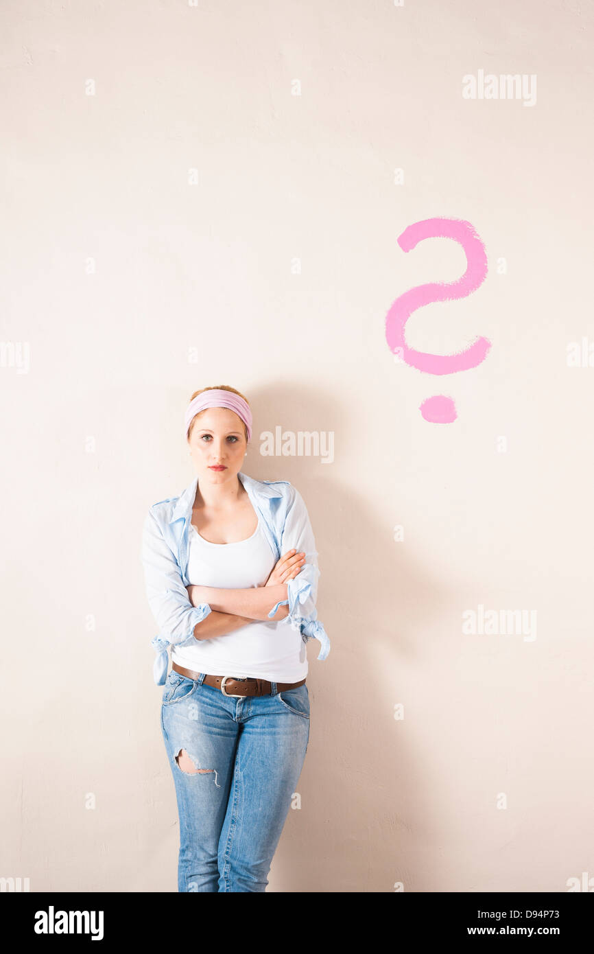 Studio Shot of Young Woman Leaning Against Wall with Question Mark Banque D'Images