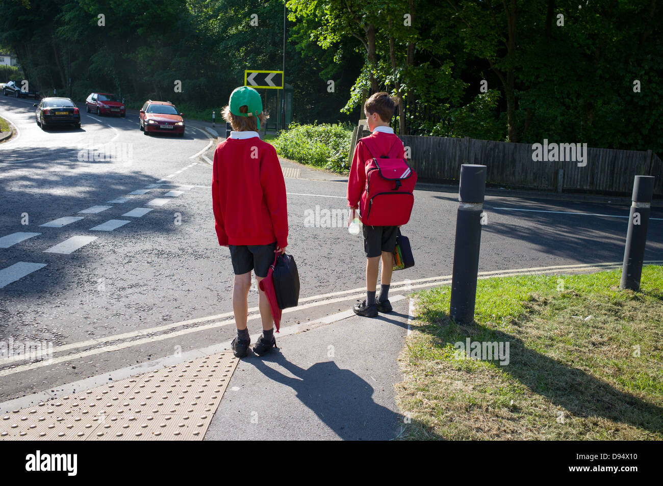 Deux jeunes garçons font leur chemin de l'école à pied et traverser la route Banque D'Images