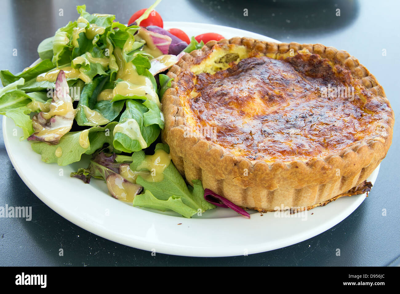 La quiche lorraine pâte avec un mélange de vert et salade de tomates closeup Banque D'Images