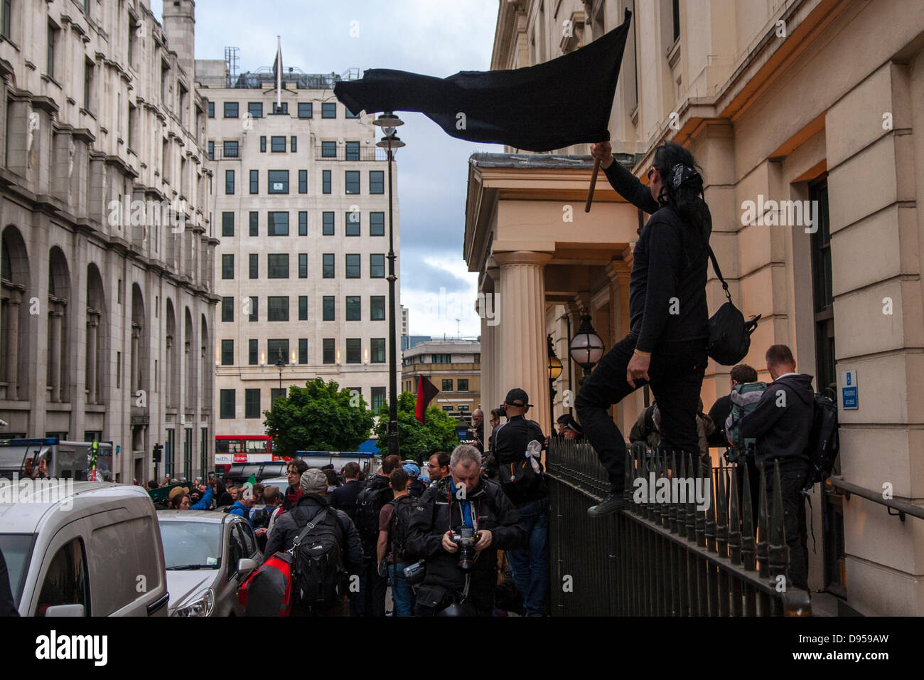 Londres, Royaume-Uni. 11 Juin, 2013. Un anarchiste vagues son drapeau tandis que, debout sur le parapet en dehors de Charing Cross station de police où plusieurs manifestants arrêtés lors des manifestations contre le sommet du G8. Crédit : Paul Davey/Alamy Live News Banque D'Images