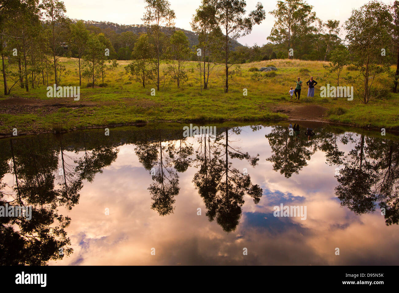 Profitez d'un groupe familial en début de soirée à pied par un étang entouré d'arbres, de l'Australie, Nouvelle Galles du Sud Banque D'Images