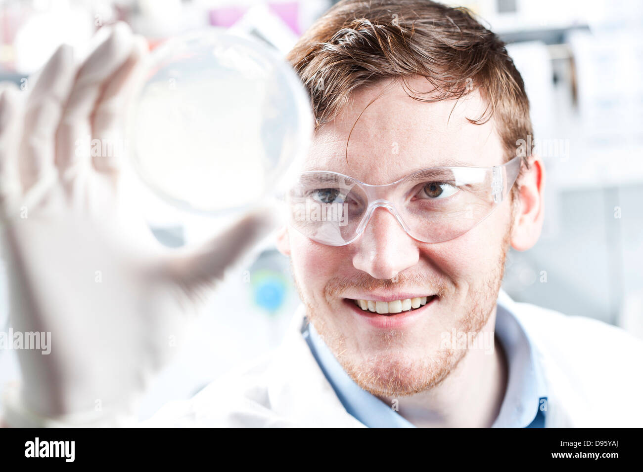 Allemagne, jeune scientifique contrôle petri desh, smiling Banque D'Images
