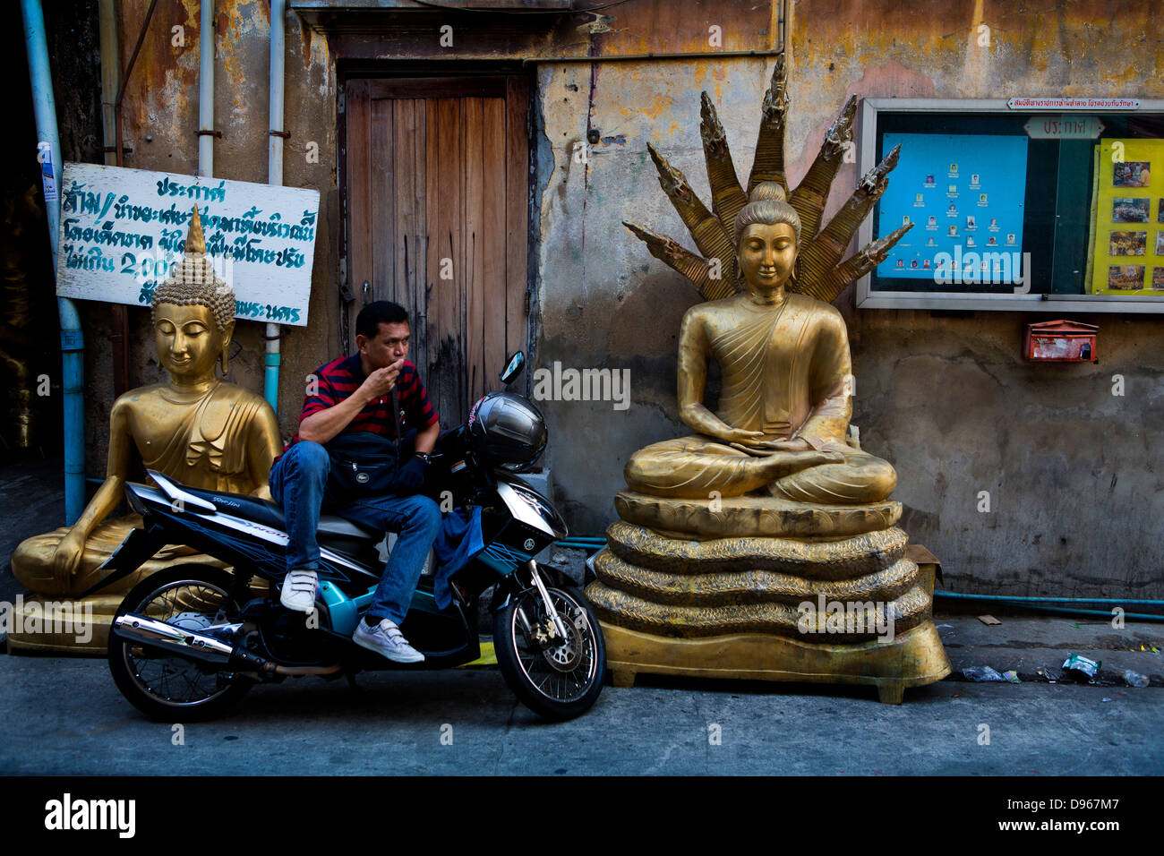 L'homme se reposant sur moto dans la région de Bangkok en icônes bouddhiste et hindoue Banque D'Images