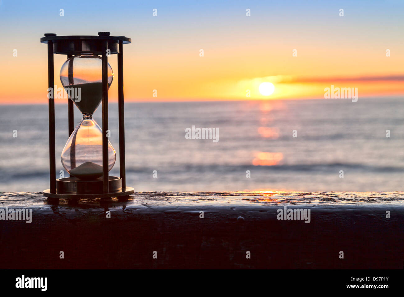 Sablier ou horloge de sable en face d'un merveilleux clair lever ou le coucher du soleil. Banque D'Images