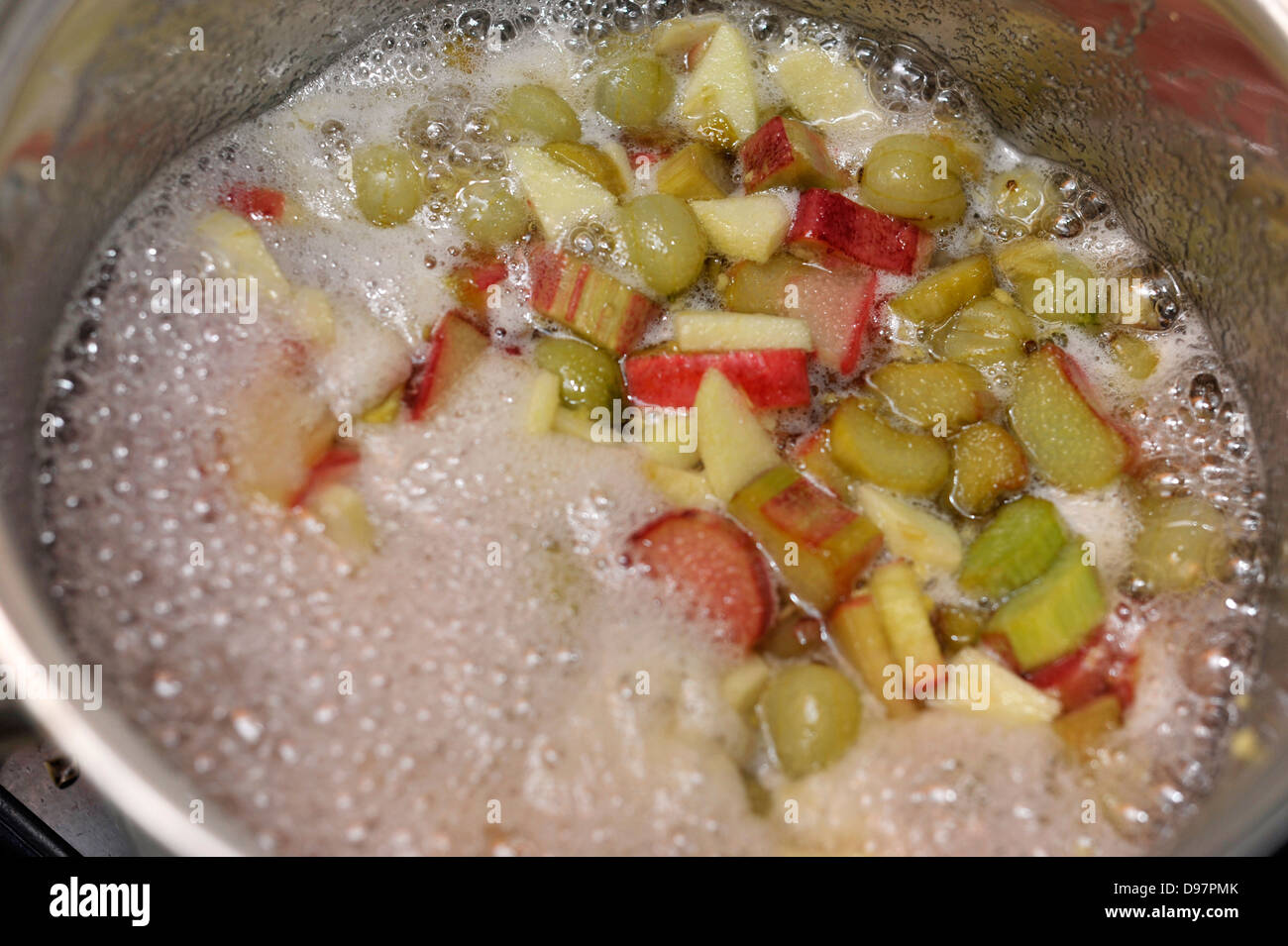 Faire de la confiture fait maison avec de la rhubarbe, groseilles et une petite pomme venant à l'ébullition. Banque D'Images