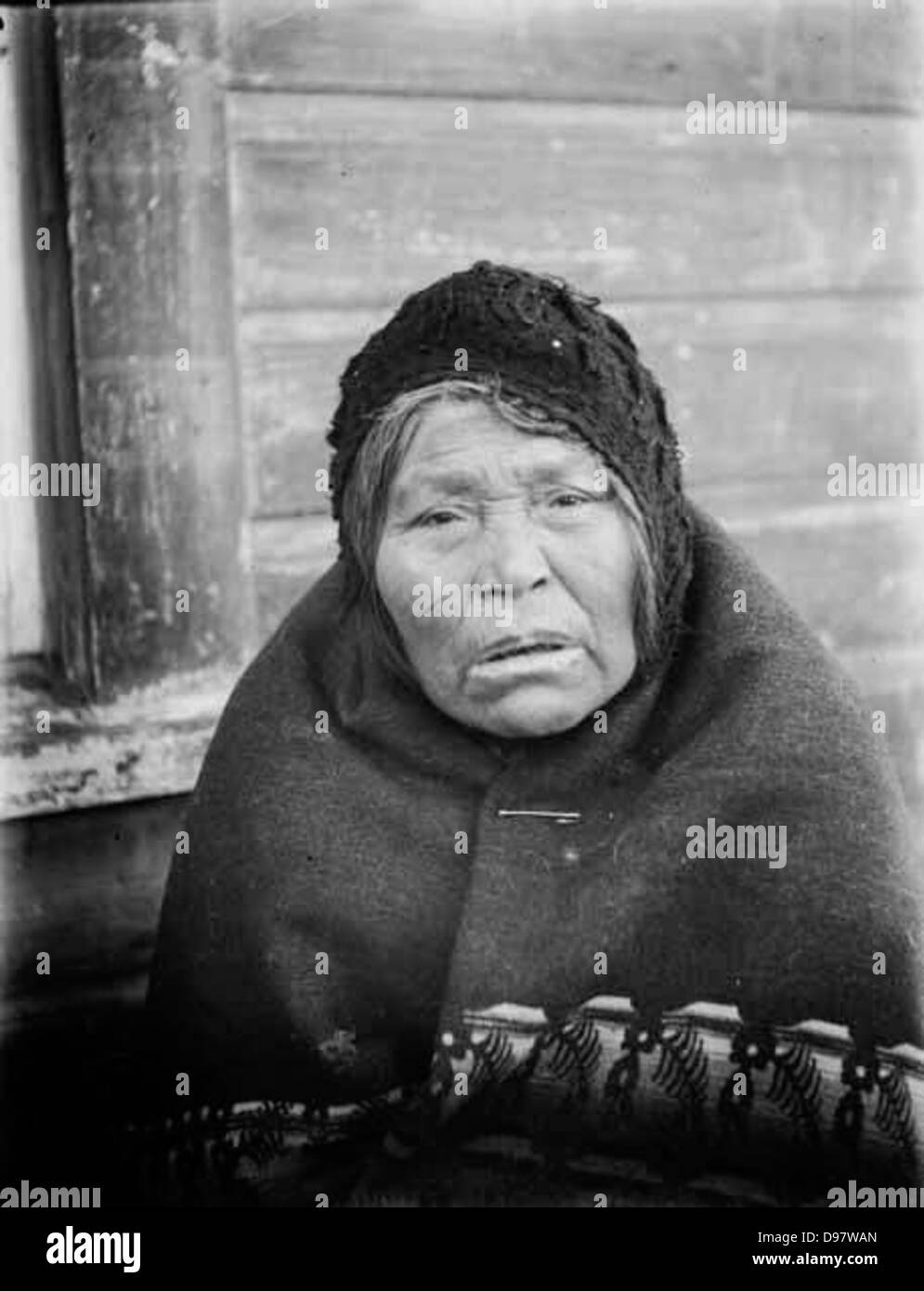 MRS Clallum Jackson, une femme Makah, est photographiée portant une casquette et une couverture à Neah Bay, Washington. L'image met en valeur les tenues vestimentaires et le patrimoine culturel des Amérindiens. Banque D'Images
