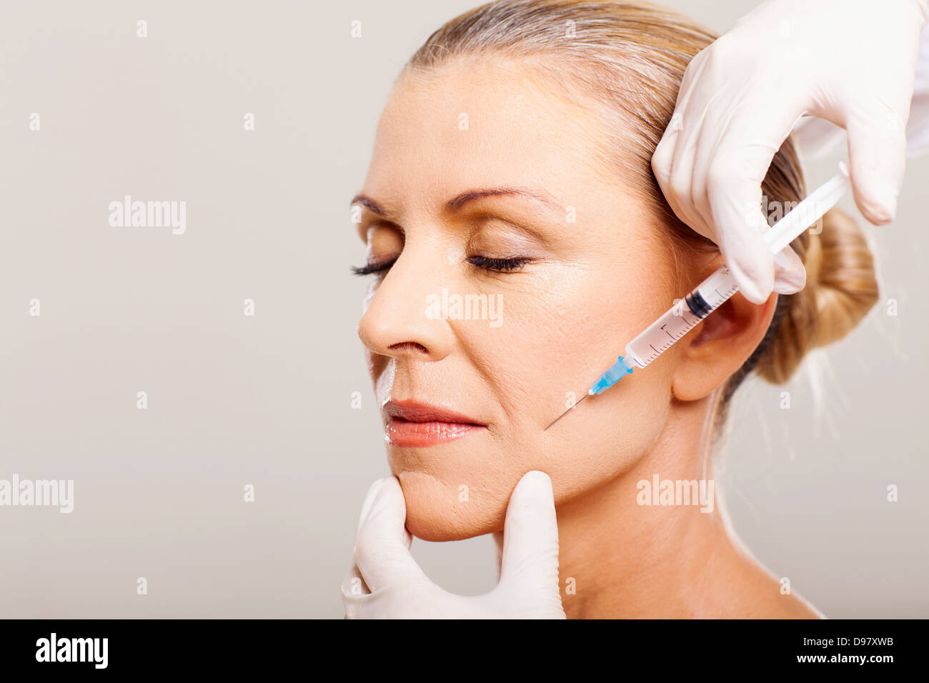 Senior woman doing face levée sur sa joue Banque D'Images